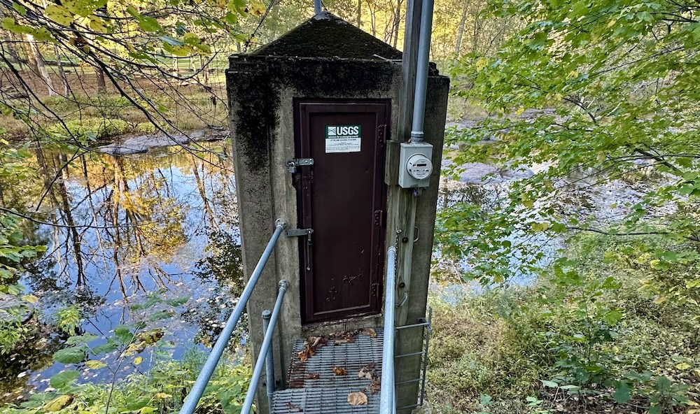 Two-level concrete gagehouse on Tohickon Creek with steel bridge leading to door on upper level.